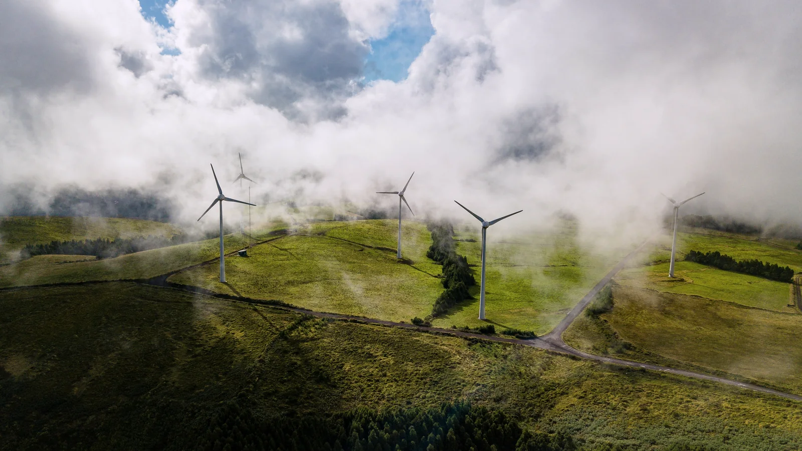 Wind turbines amid low cloud and hills.