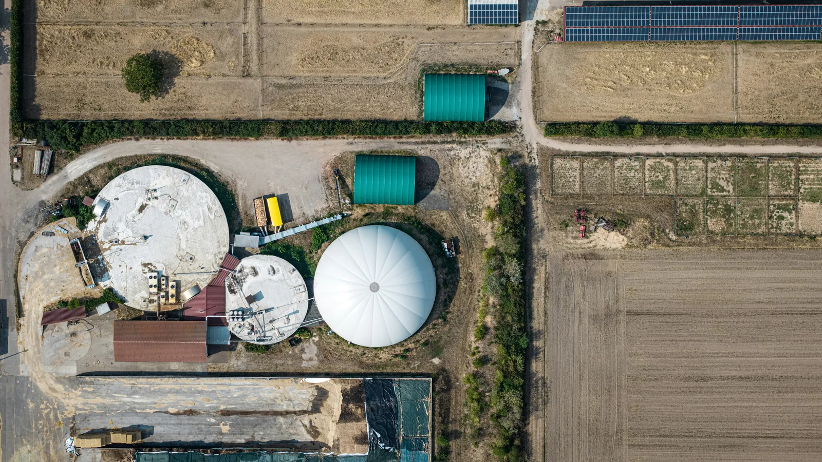 Aerial photograph of a biogas installation with solar panels nearby.